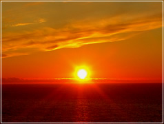 初夏の広大な海が真っ赤に染まる夕陽